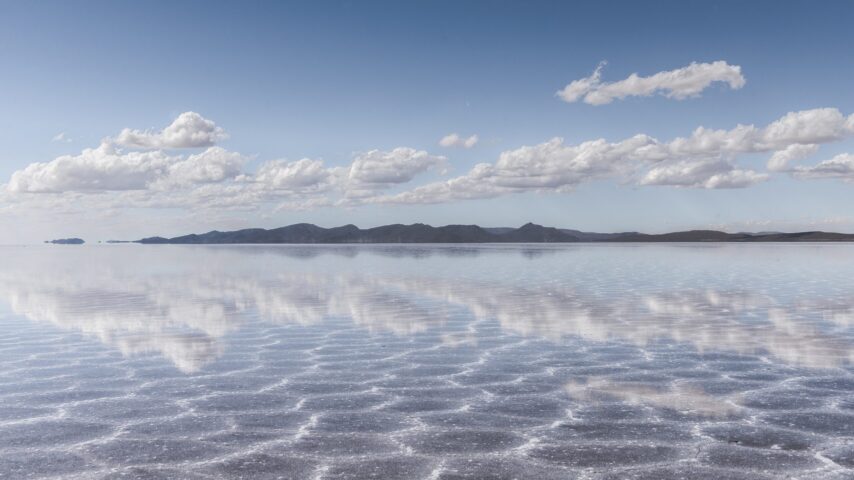 The sand texture visible under the crystal clear sea and the sky in the background
